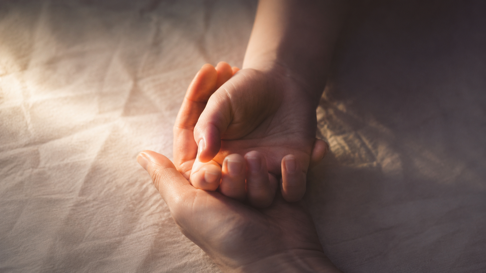 Deux mains entrelacées en geste d'auto-compassion — métaphore de l'enfant intérieur, trauma d'enfance à l'âge adulte